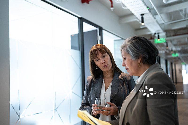 商务人士在办公室走廊边走边谈图片素材