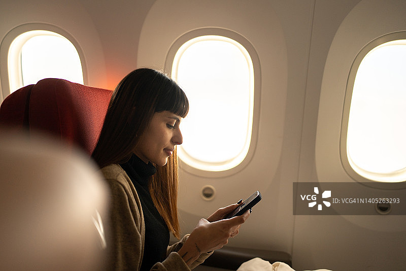 乘飞机使用手机的年轻女子图片素材