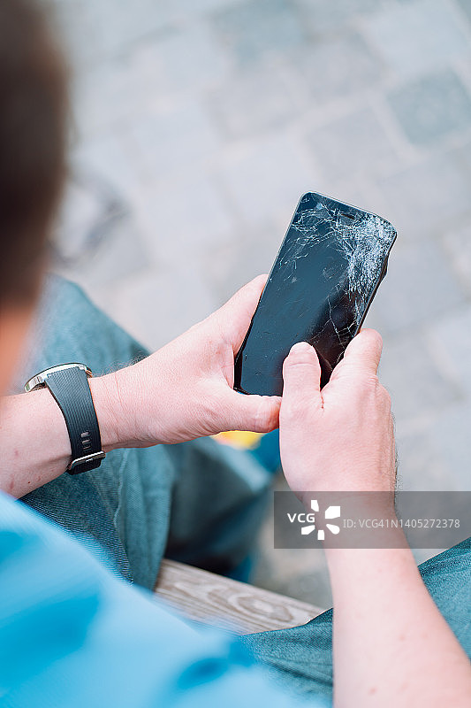 男子检查损坏的黑色智能手机图片素材