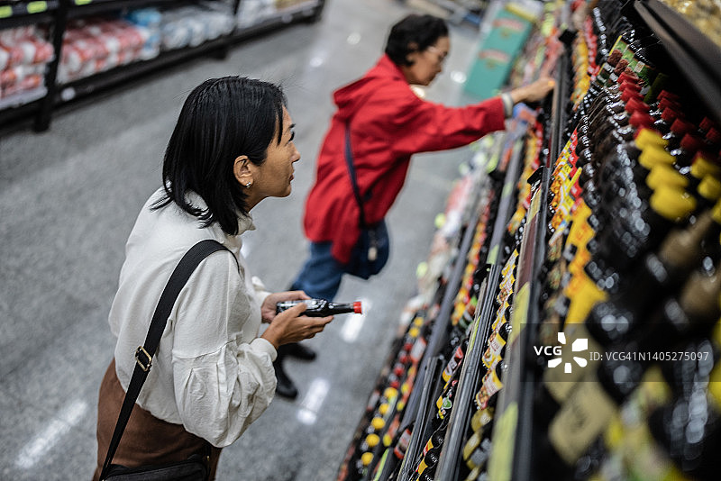 中年妇女在超市购买酱油图片素材