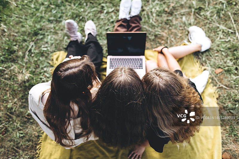 一群青少年在阳光明媚的日子里用笔记本电脑在线学习或在大自然中做作业。图片素材