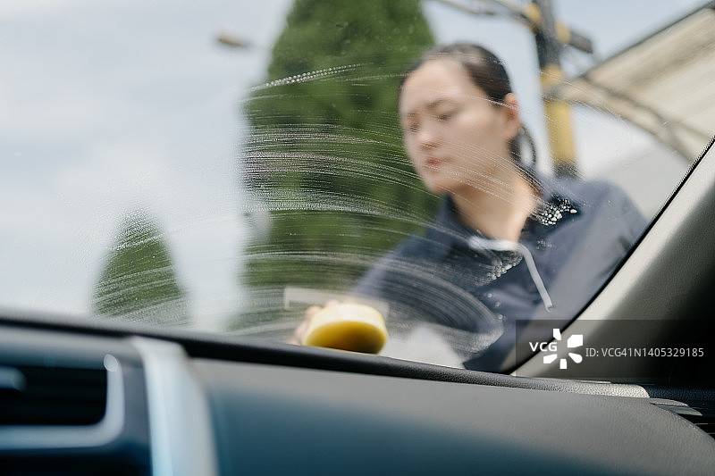 正在清洁汽车玻璃的亚洲年轻女人图片素材