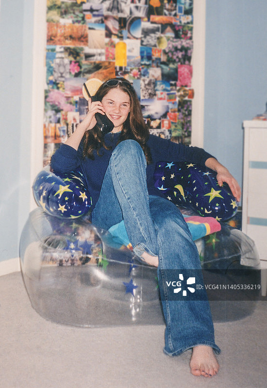20世纪90年代至21世纪初，青少年坐在充气椅上打电话图片素材