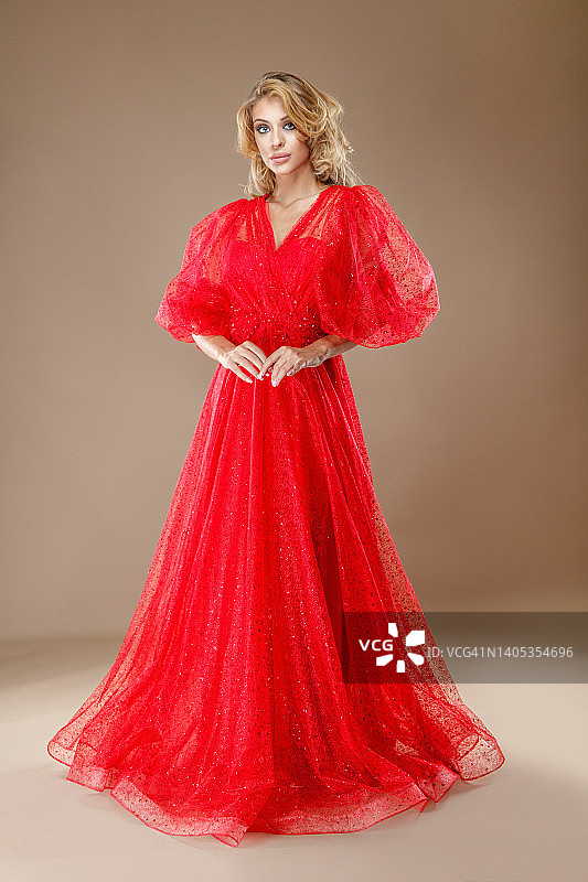 年轻金发时尚模特身穿红色蕾丝长裙，看着镜头。图片素材