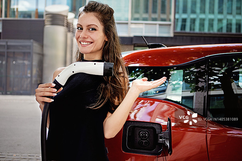 正在充电的电动汽车旁的女子肖像图片素材