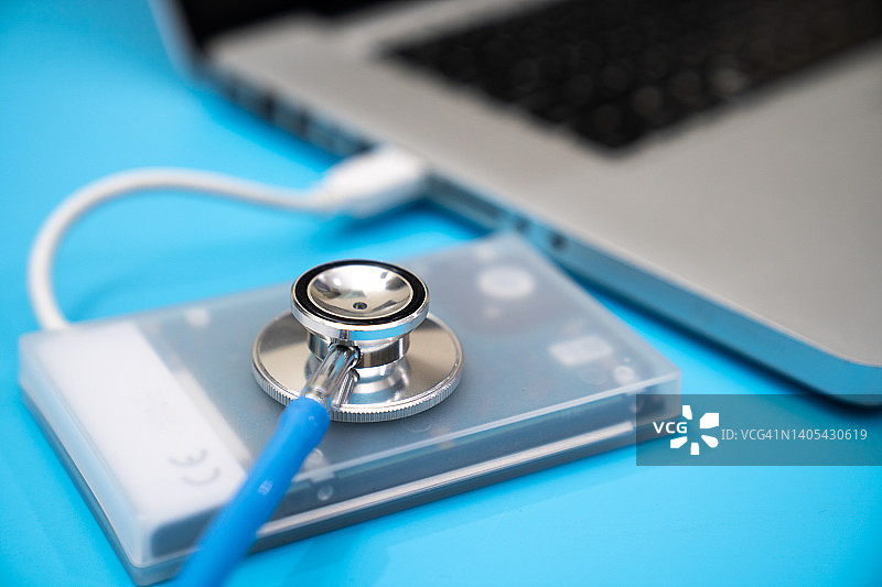 蓝色背景上连接笔记本电脑的移动硬盘，数据、硬件和信息技术概念图片素材