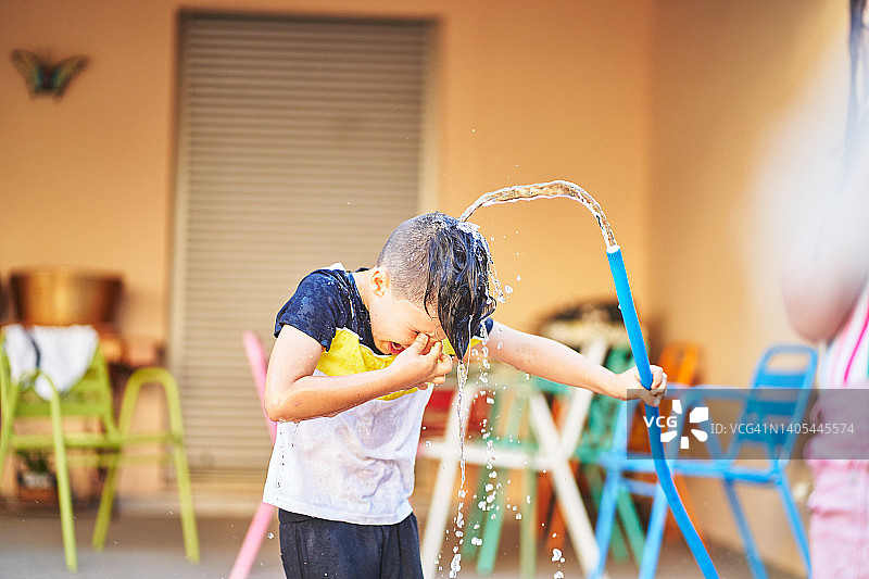 无忧无虑的男孩往头上浇水图片素材