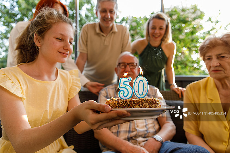 微笑的少女手捧插着50岁生日蜡烛的蛋糕图片素材