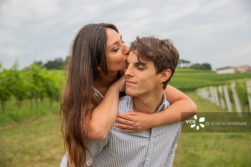 葡萄园里相拥的年轻情侣，女孩亲吻爱人的额头图片素材