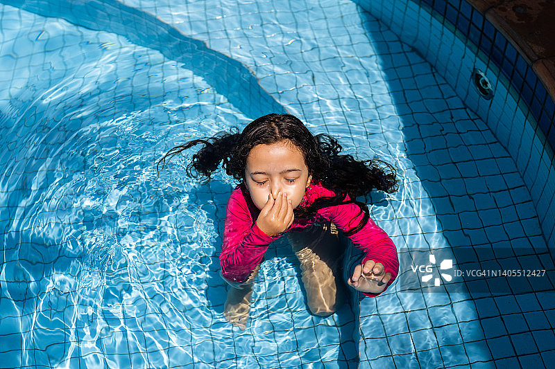 在游泳池里捂住鼻子的女孩图片素材