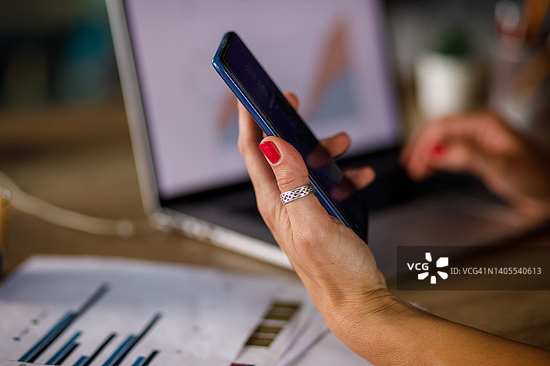 女人在办公桌前工作时用智能手机通话图片素材