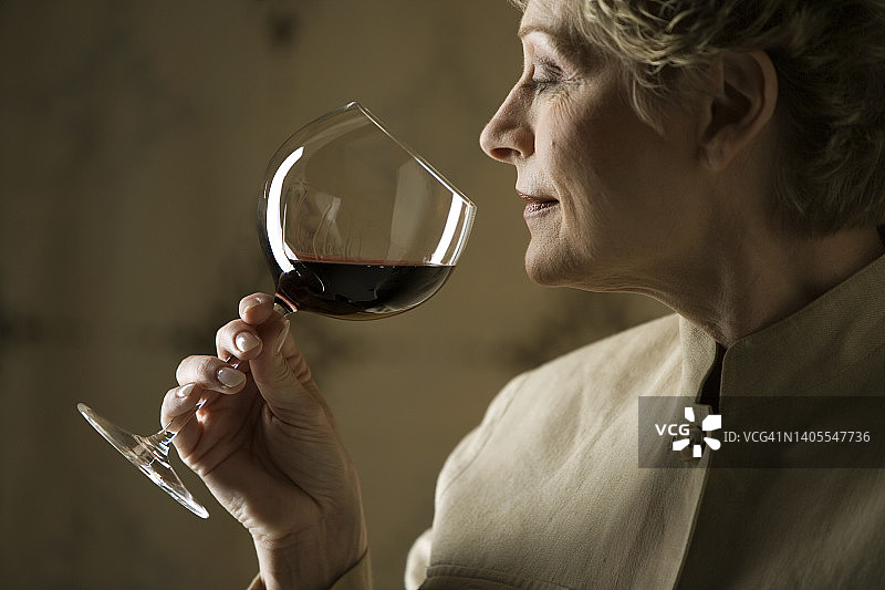女人闻着红酒杯图片素材
