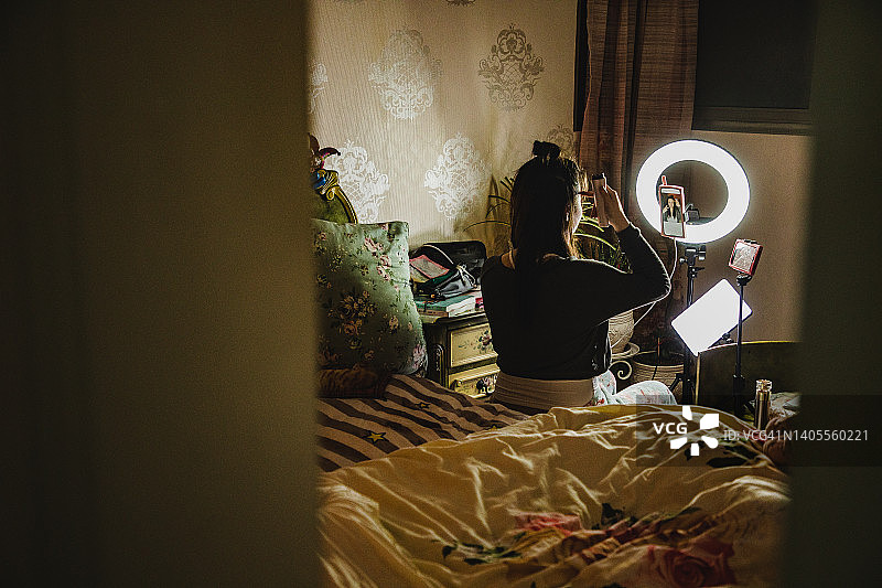 亚洲女性网红在卧室用手机录制日常护肤流程图片素材