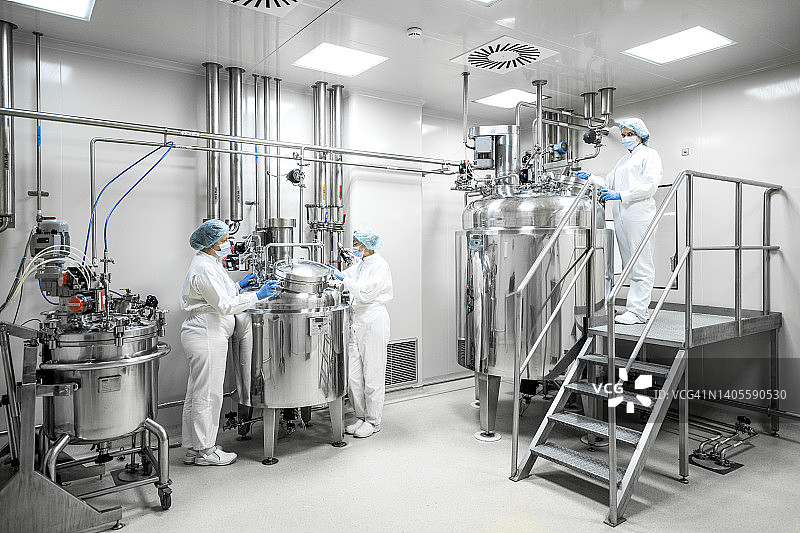 制药实验室内身穿防护服的三名全副武装的员工图片素材