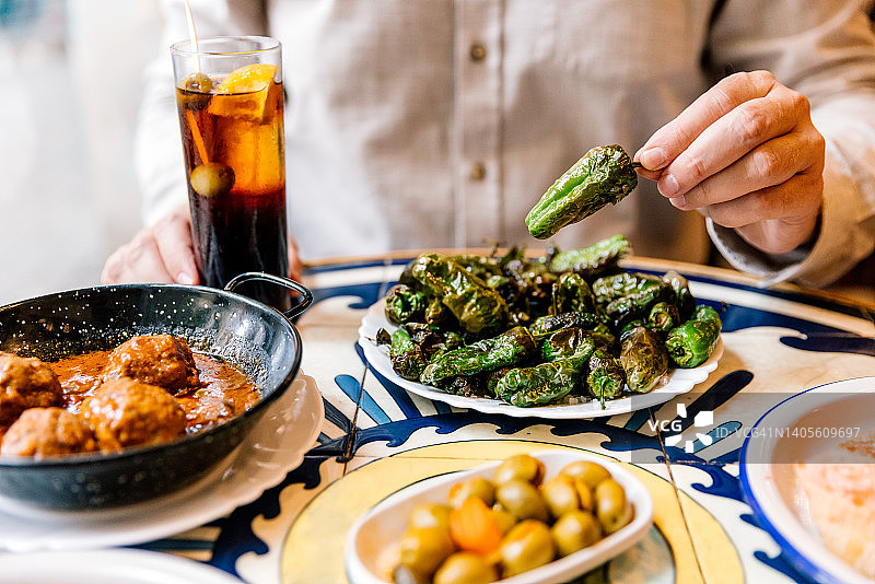 男人在西班牙巴塞罗那的餐吧里吃炸青椒，喝味美思酒图片素材