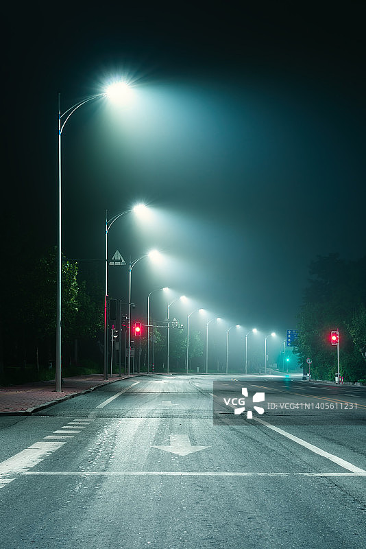 昏暗有雾的夜晚，灯光照耀下的幽深道路仰视角度图片素材