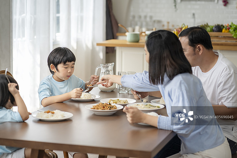 亚洲家庭在餐桌上吃饭，反映家庭内部的良好关系图片素材
