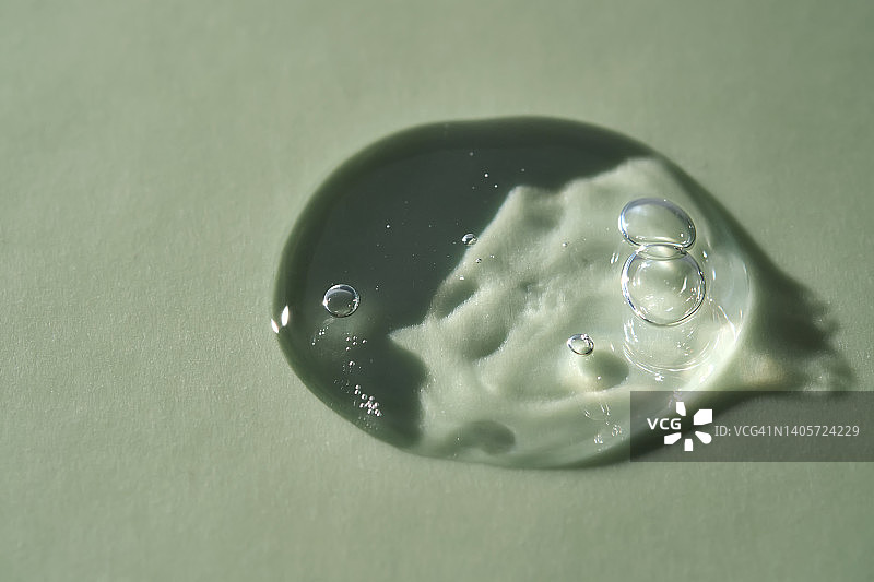 绿色背景上的一滴化妆品液体凝胶或卸妆水图片素材