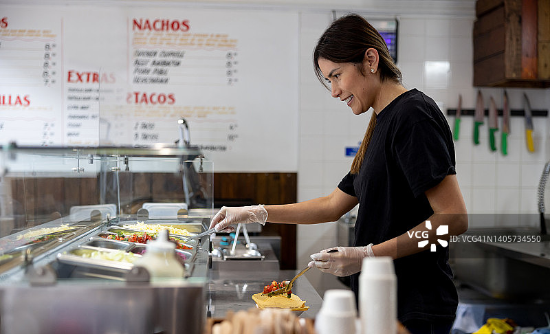 在墨西哥餐厅工作并制作玉米卷的快乐女人图片素材