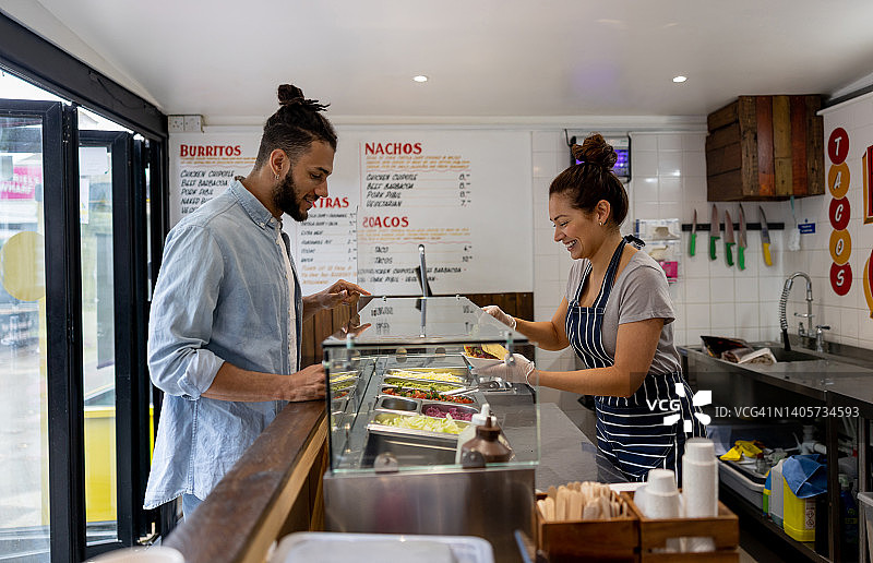 快乐的女服务员在墨西哥小餐馆为顾客提供玉米饼图片素材