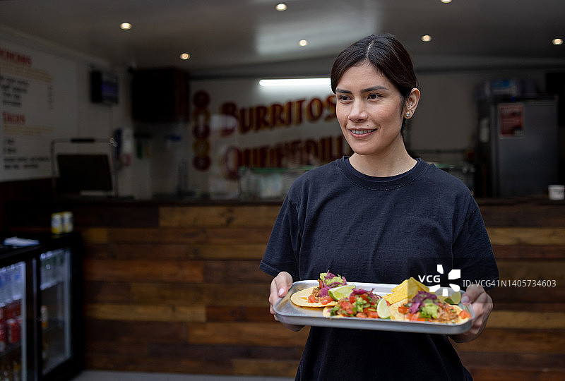 在墨西哥餐厅供应玉米卷的女服务员图片素材