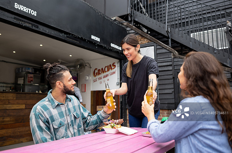 在墨西哥餐厅工作的服务员为顾客提供啤酒和炸玉米饼图片素材
