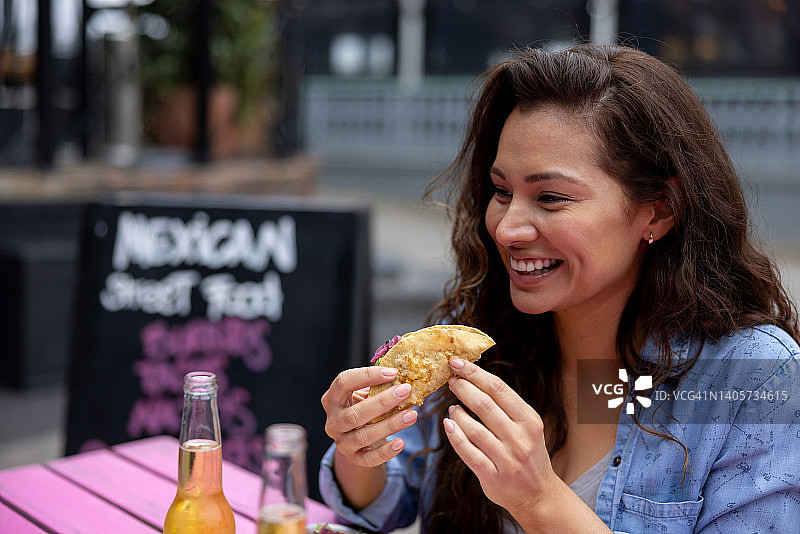 快乐的女人在墨西哥餐厅吃玉米卷图片素材