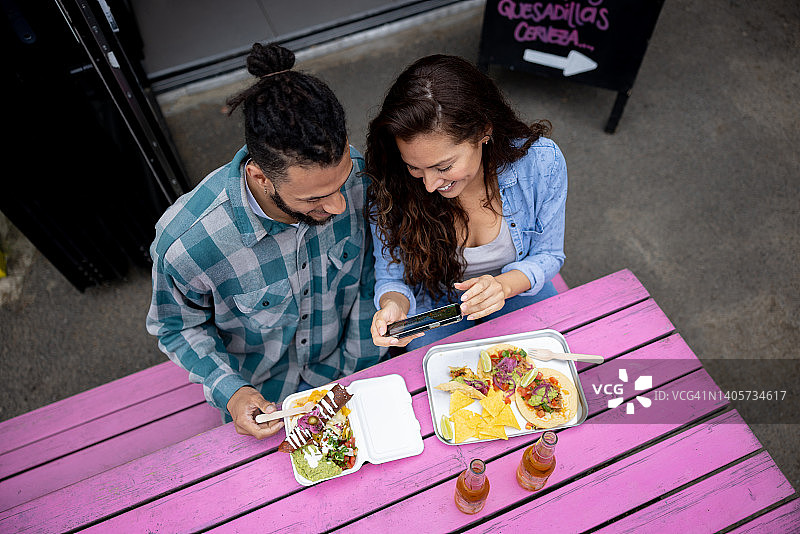 情侣在墨西哥餐厅吃炸玉米饼时观看社交媒体视频图片素材