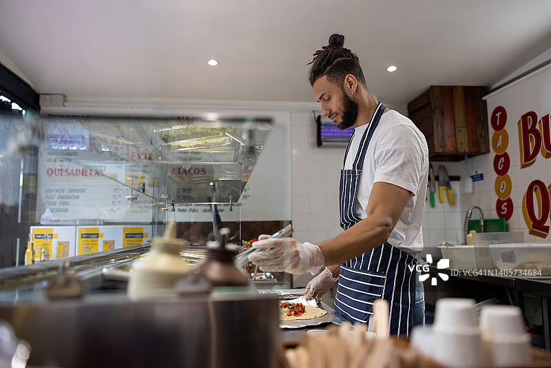 男人在墨西哥餐厅工作时制作墨西哥卷饼图片素材