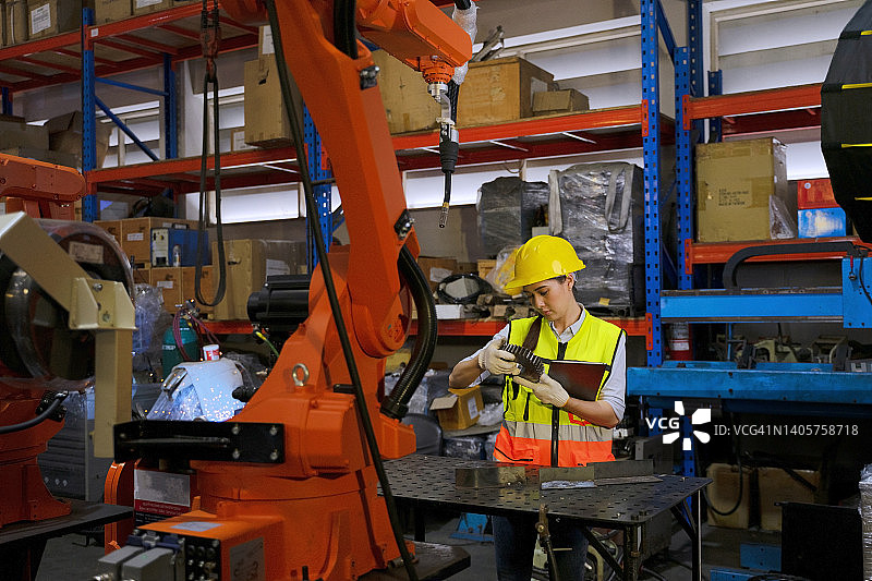 员工在工厂使用机械臂工作。图片素材