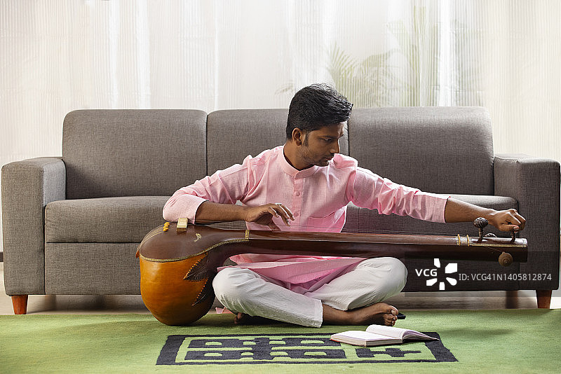 在客厅里调整坦普拉琴的年轻男音乐家图片素材