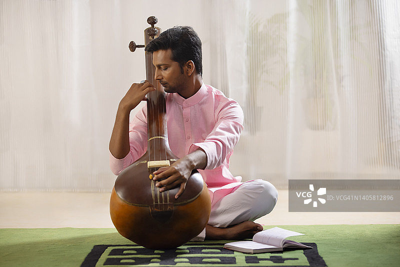 在客厅里调整坦普拉琴的年轻男音乐家图片素材