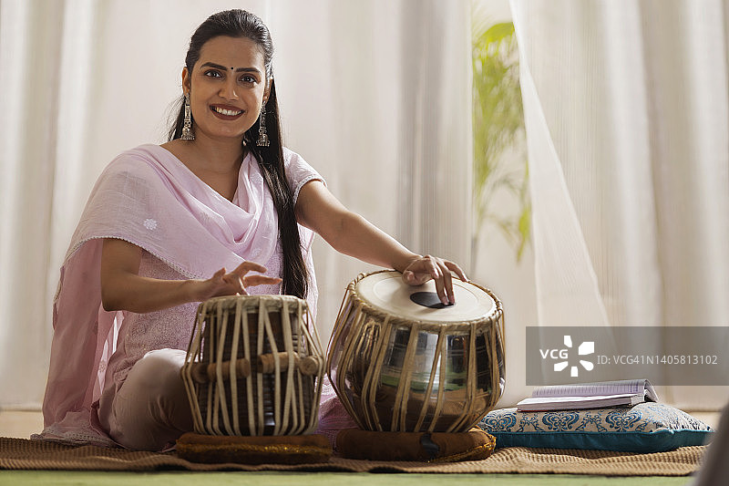 在家弹奏塔布拉鼓的年轻女子肖像图片素材