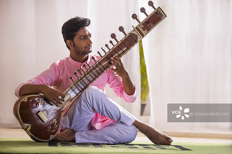 年轻男子在家弹奏锡塔琴图片素材