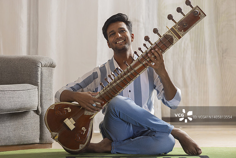 年轻音乐家在家弹奏西塔琴肖像图片素材