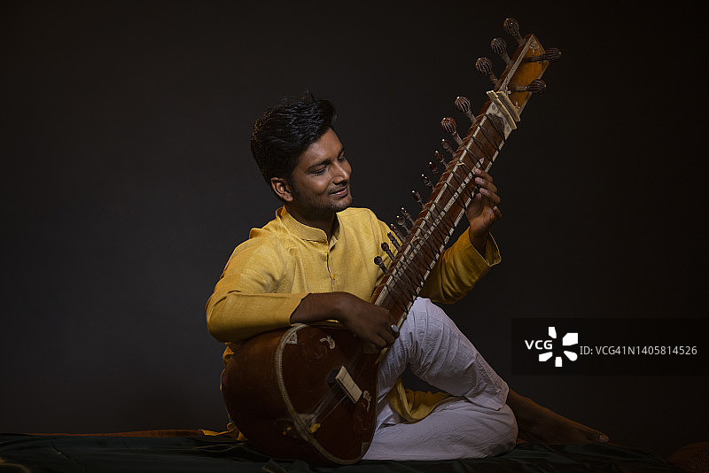 在音乐会上用西塔琴表演的青年男子肖像图片素材