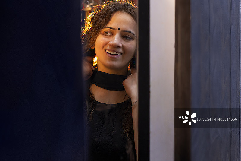 年轻女子在家中对着镜子穿衣服图片素材