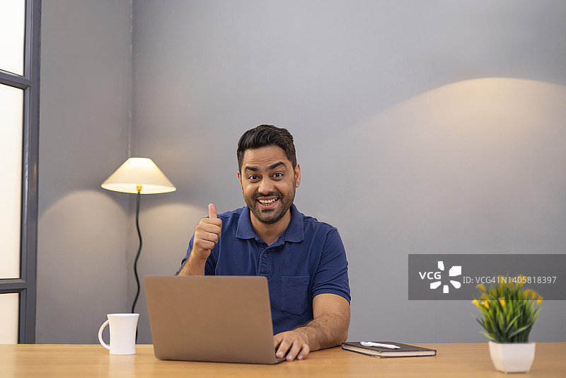 在家办公的自由职业男子对着笔记本电脑竖起大拇指图片素材