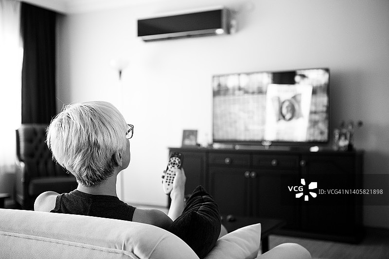 一名女子使用遥控器观看电视图片素材