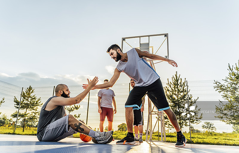 男人帮助受伤的队友起身图片素材