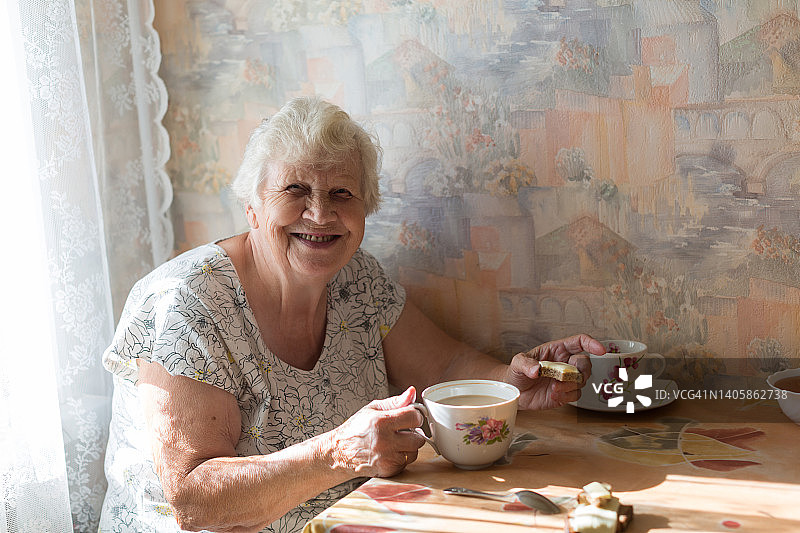 老年妇女在厨房喝咖啡吃三明治图片素材