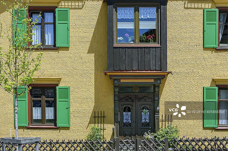 带凸窗和绿色百叶窗的黄色木瓦外墙，德国巴伐利亚阿尔高上斯陶芬图片素材