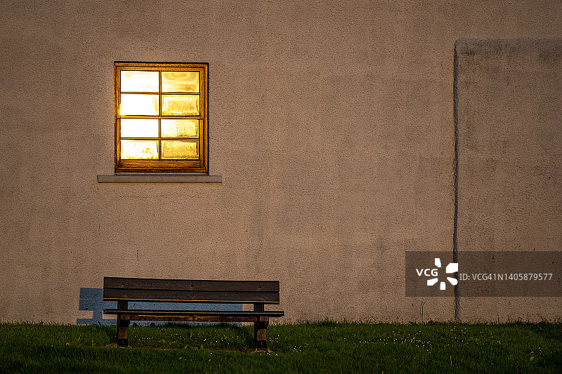 简洁外墙上被照亮的窗户和长凳图片素材
