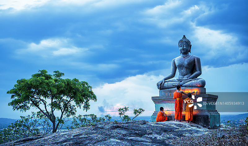 在佛教寺庙中点燃蜡烛的年轻新手僧侣图片素材