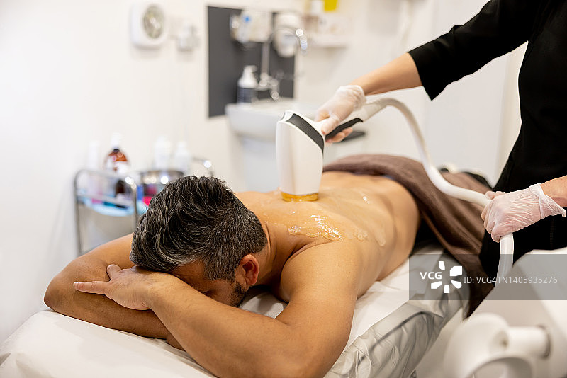 在水疗中心接受背部脱毛护理的男人图片素材