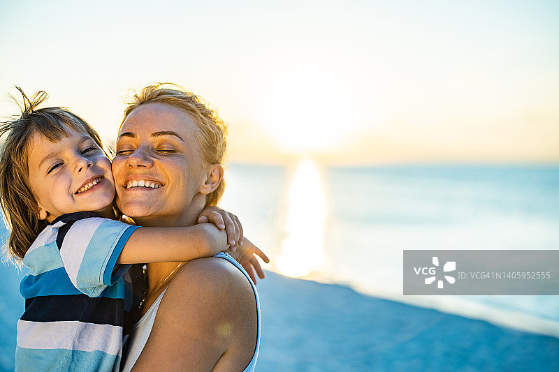 在海滩上拥抱的单亲母亲和儿子图片素材