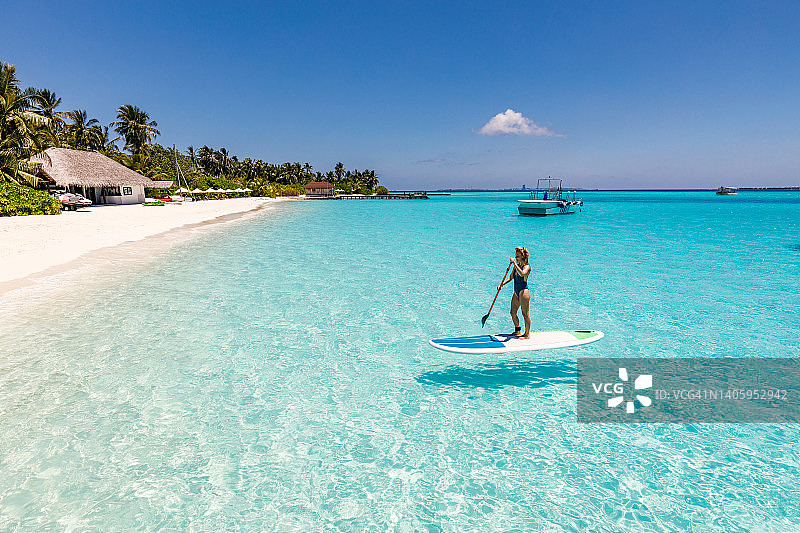 年轻女人在夏日海边享受桨板运动图片素材
