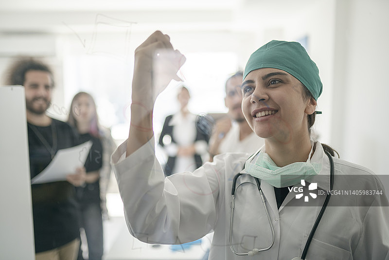 女医生在会议室用笔在玻璃板上书写图片素材