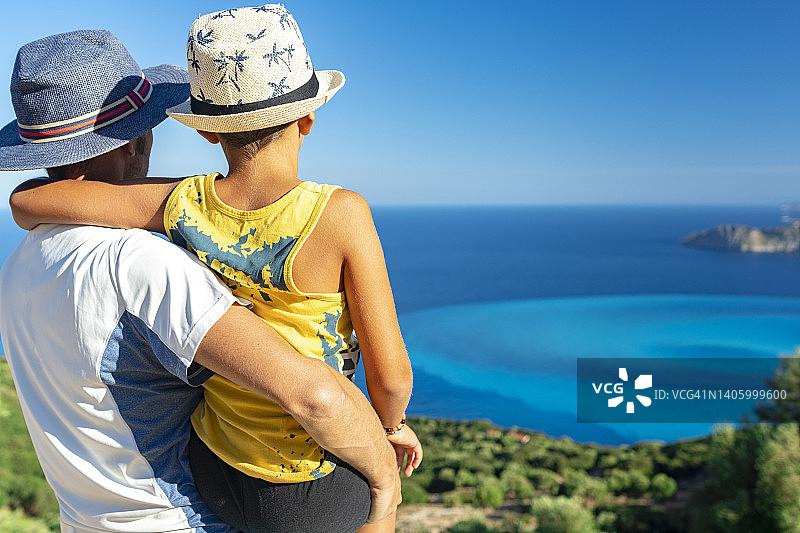 快乐的父亲抱着小男孩看着大海图片素材