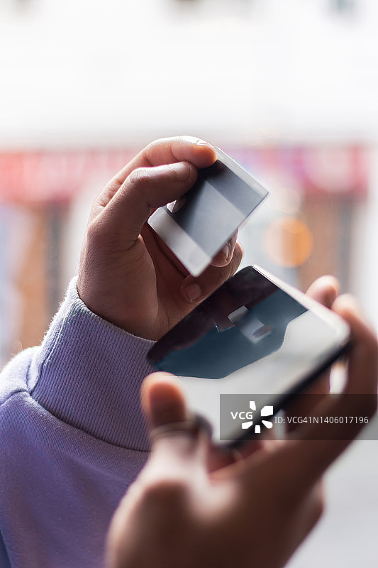 男人使用智能手机并持有信用卡，象征购买力、通货膨胀等图片素材